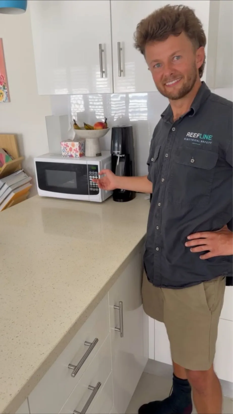 A Reefline electrician in a kitchen beside a microwave